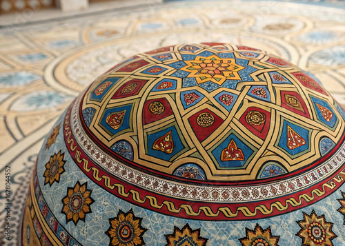 Detailed close-up of a colorful kippah with an intricate Islamic geometric pattern, showcasing its rich texture against a blurred mosaic floor background.