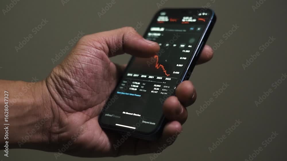 close up smartphone with stock exchange, trading Online app interface. Man hand scrolling touch screen analysing chart forex crypto currency.