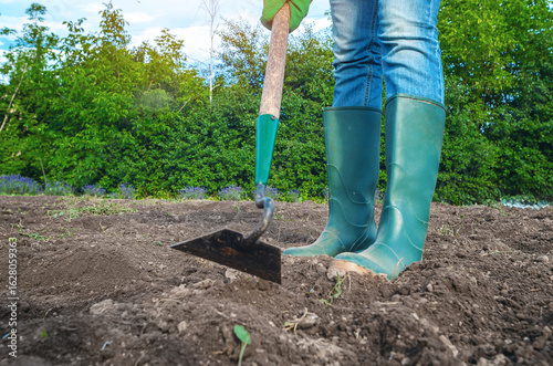 Canvas-taulu Woman in jeans working with hoe on soil