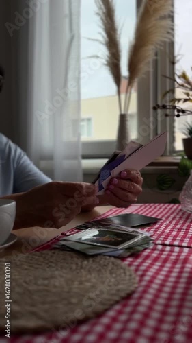 elderly woman’s hands gently flipping through old photographs, remembering the past