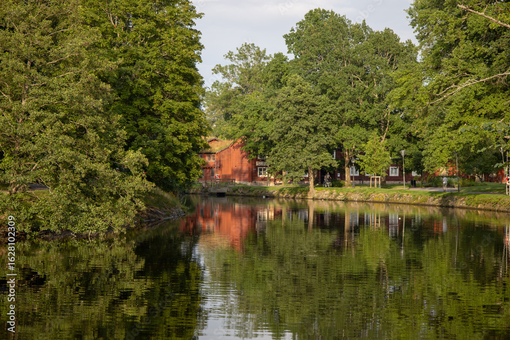 Obraz premium Scenic view of Orebro parks next to the flowing creek surrounded by natural greenery in central Sweden Orebro County