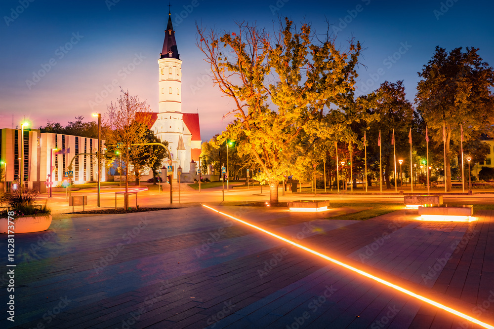 Fototapeta premium Illuminated night view of empty square with St. Peter and Paul cathedral on background. Amazing summer cityscape of Siauliai town, Lithuania, Europe. Traveling concept background.