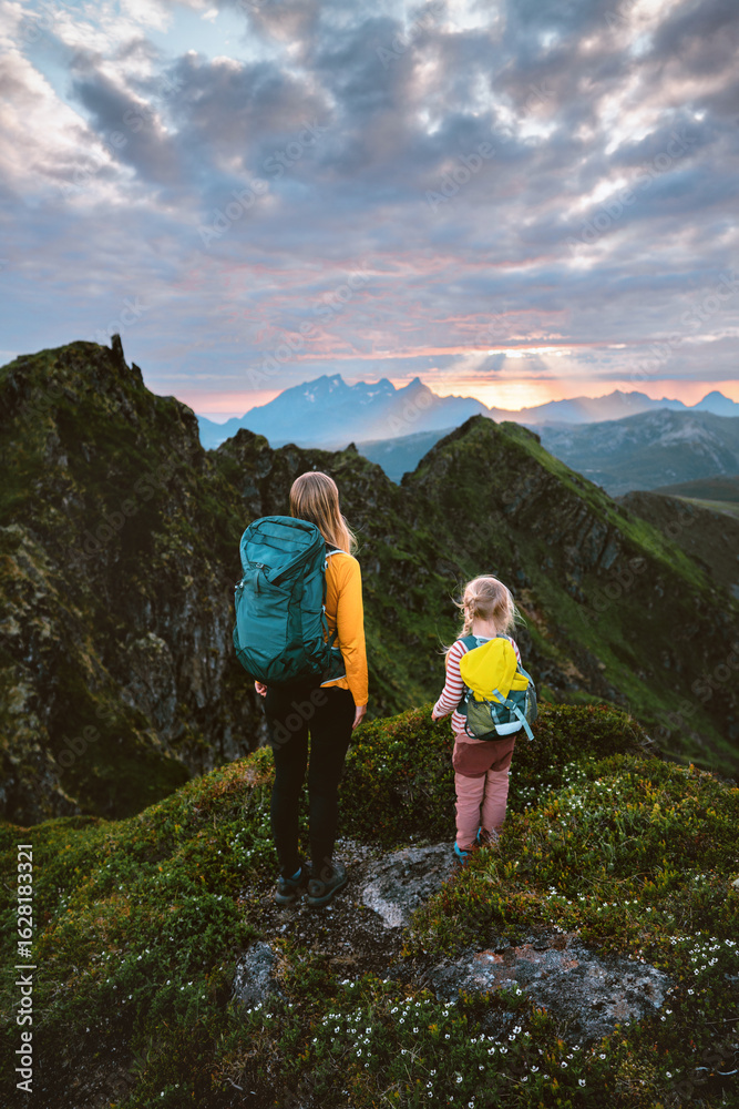 Fototapeta premium Family mother and daughter travel in Norway - hiking in mountains exploring Lofoten Islands on summer vacations backpacking camping trip, parent and kid climbing together enjoying sunset view