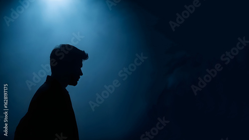 Silhouette of a young man in a dark room