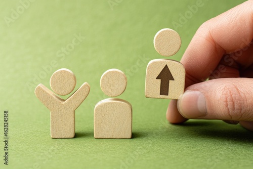 Hand placing a wooden figure with an upward arrow, signifying career advancement,  amongst two other figures