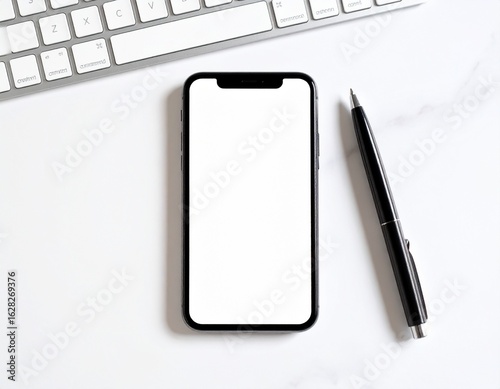 Overhead shot of a smartphone with a blank screen, keyboard, and pen on a white surface.