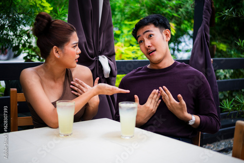 Angry girlfriend confronts her defensive boyfriend during a date at an alfresco cafe. Pent up frustration between a young couple.