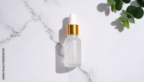 Frosted glass dropper bottle on a marble surface with greenery.