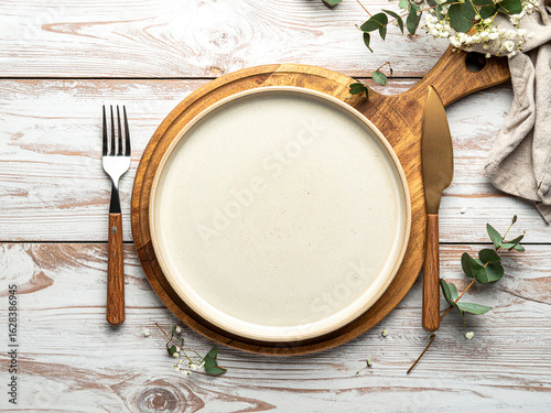 Top-Down View of Handmade Ceramic Plate with Wooden Cutlery on Rustic Table in Warm Natural Light