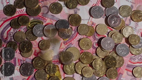 Many coins fall on top of the banknotes