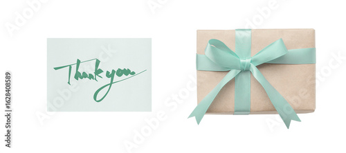 Overhead view of a green ribbon gift box next to a thank you card with green handwritten text