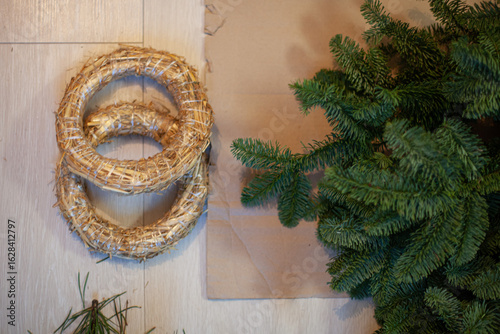 Billede på lærred Top view of natural materials for christmas wreath: bunch of noble fir branches and straw bases, lying on floor