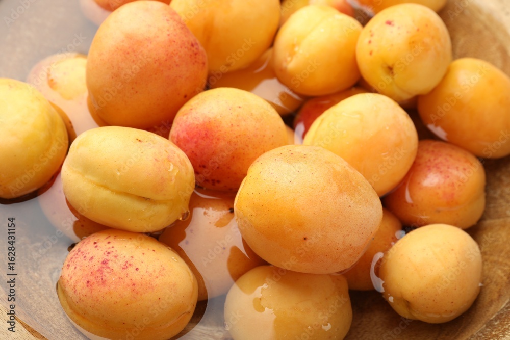 Fresh ripe apricots in wooden bowl with water, above view Fresh ripe apricots in wooden bowl with water, above view