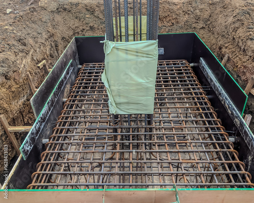 Fényképezés Steel reinforcement for concrete column and footing at construction site, showing detailed rebar arrangement and formwork before concrete pouring