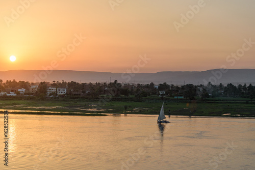 Принти на полотні Silhouetted felucca on the Nile with the sun above the hills, Luxor
