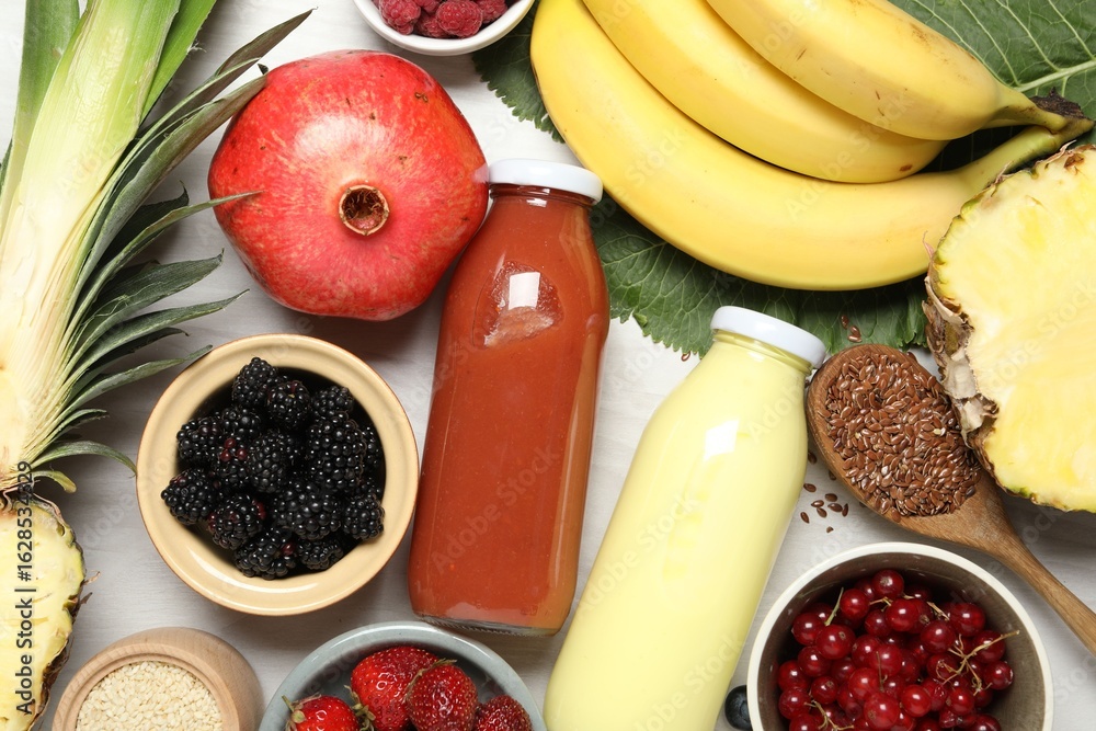 Fototapeta premium Superfood. Bottles with tasty smoothies and ingredients on light wooden table, flat lay