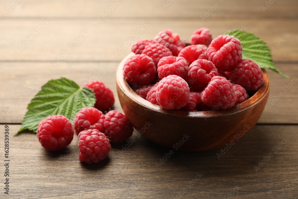 Tasty fresh ripe raspberries and leaves on wooden table, closeup Tasty fresh ripe raspberries and leaves on wooden table, closeup