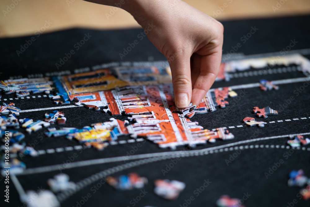 Fototapeta premium Female hand solving jigsaw puzzle close up