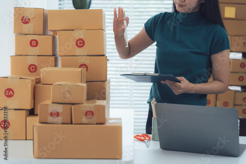 Vászonkép Online Shop Owner: A dynamic businesswoman meticulously manages her online shop, surrounded by stacks of packaged goods, embodying the fast-paced world of e-commerce, efficiency