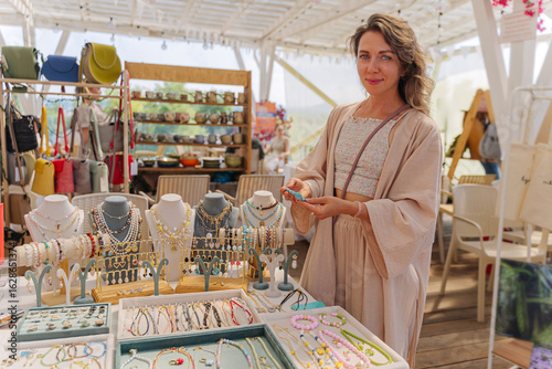 Local Artisan Selling  Jewelry at Creative Market. Handmade Jewelry Seller Demonstrating Accessories. Artisanal Goods, Ceramics, Candles.