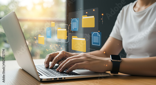 Typing on a laptop with file folder icons floating above, representing digital document management, data storage, and efficient information organization in the cloud