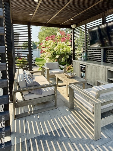 Modern indoor outdoor living entertainment space and patio under a pavilion pergola. poolside equipped with bar and gas fire pit with cascading waterfall. Chair sofa couch and table. Hotel resort feel