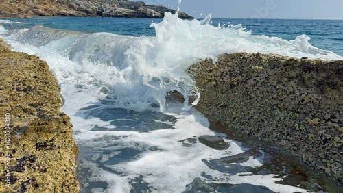 Small waves gently splash through natural stone slabs on Kory Beach in Alanya, Turkey. Peaceful seaside view perfect for travel, relaxation, and nature themes