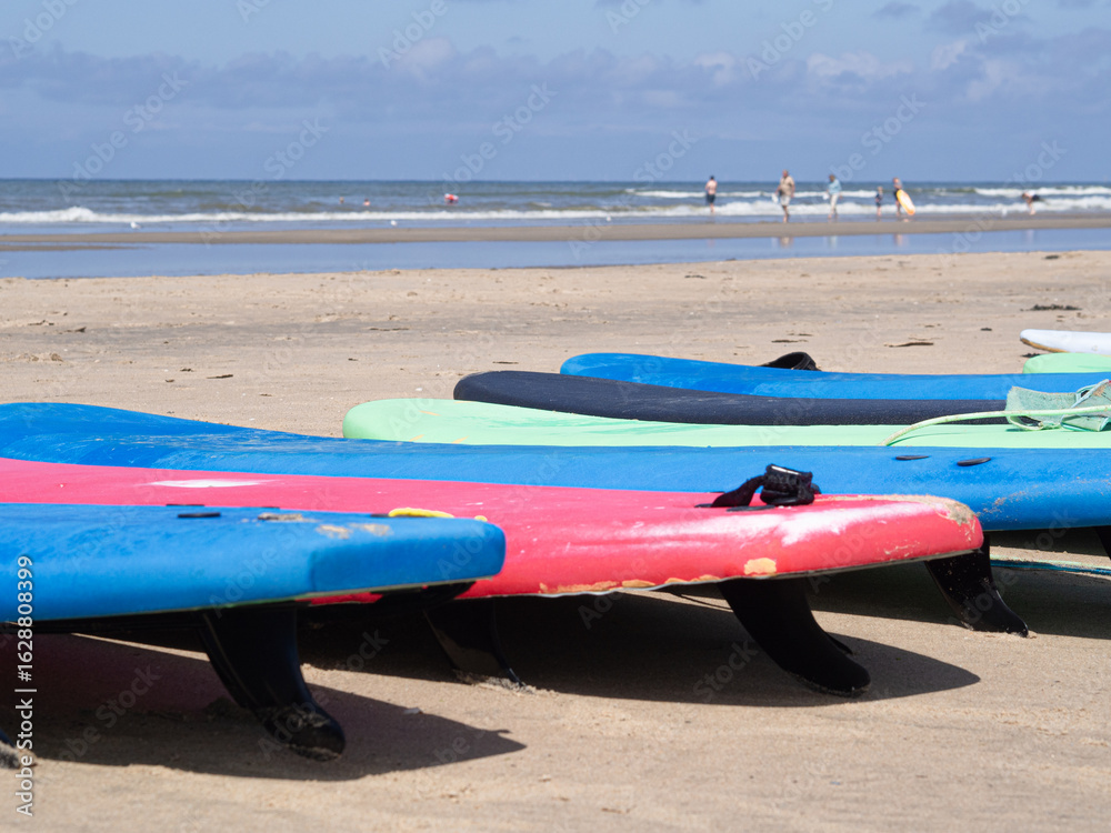 Green and blue surfboards stacked near ocean waves – perfect for safety during swimming promo, surf summer camp, surf school promo, summer sports in Europe Green and blue surfboards stacked near ocean waves – perfect for safety during swimming promo, surf summer camp, surf school promo, summer sports in Europe