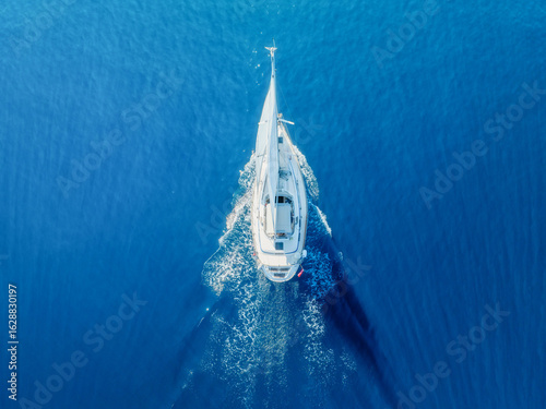 Sea and sail yacht as a background. Sea and waves from top view. Blue water background from top view. Top view from drone. Summertime vacation.