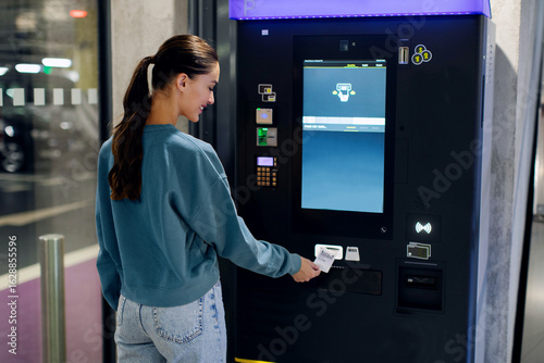 Fotografie Lady driver paying and taking ticket in parking meter near terminal in the under