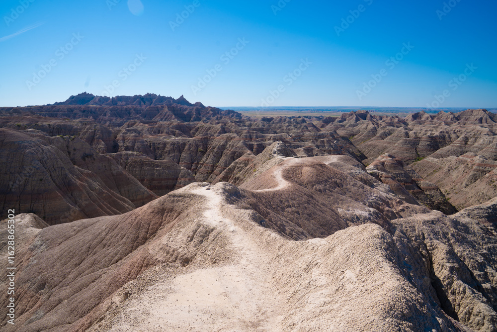 Naklejka premium Layered rock formations under clear sky in Badlands National Park, South Dakota