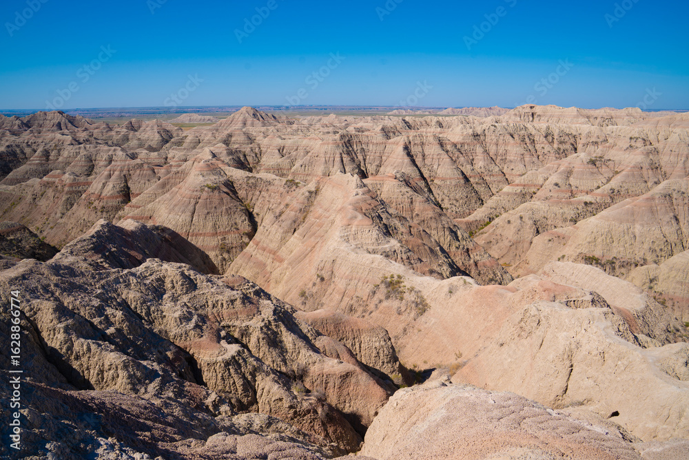 Fototapeta premium Layered rock formations under clear sky in Badlands National Park, South Dakota