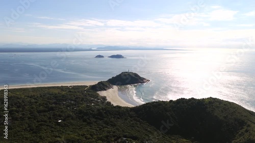 Aerial view of Ilha do Mel lighthouse peninsula with sunlight reflecting on the ocean.