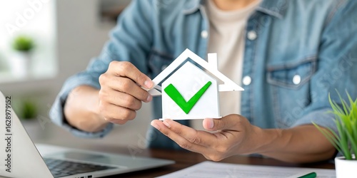 Man holding a house symbol with a green checkmark for approval