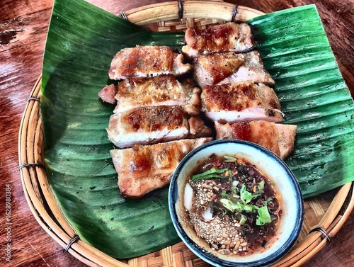 Grilled Thai Chicken with Jaew Dipping Sauce on Banana Leaf in Bamboo Tray