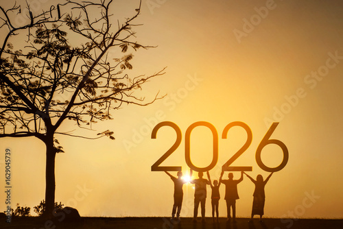 Silhouette of people holding up the year 2026 at a beautiful sunset.