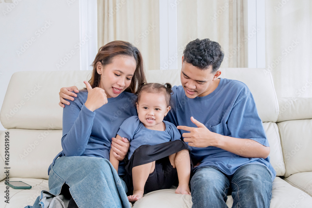 Happy parents playing with their baby daughter on the sofa at home. Happy parents playing with their baby daughter on the sofa at home.