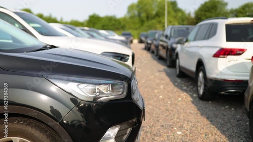 A row of various cars parked outdoors, potentially for sale or display, under a clear sky.