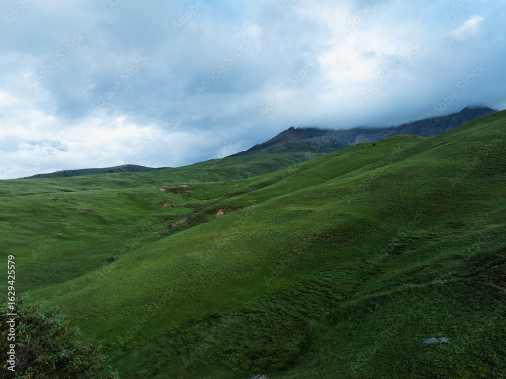 Fototapeta premium Aerial view of beautiful high altitude grassland mountains and snow capped mountain landscape in China