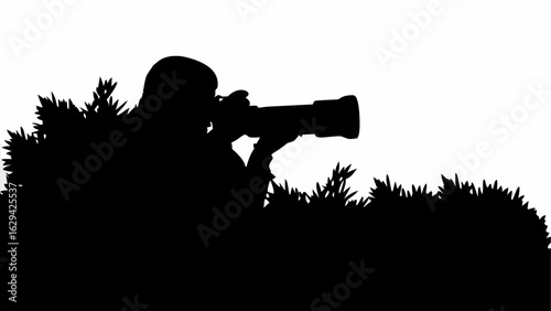 Silhouette of a photographer with a telephoto lens hiding in the grass taking a picture outdoors