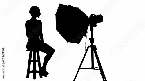 Silhouette of a model sitting on a stool with a camera and softbox in a photography studio setup