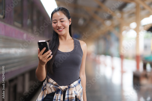 Canvas Print Young woman engaging with smartphone at train station
