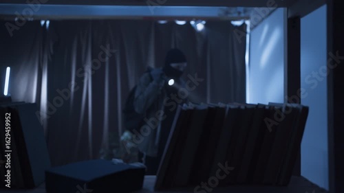 Thief in black balaclava with flashlight making housebreak. Robber criminal entering a house for money stealing at night