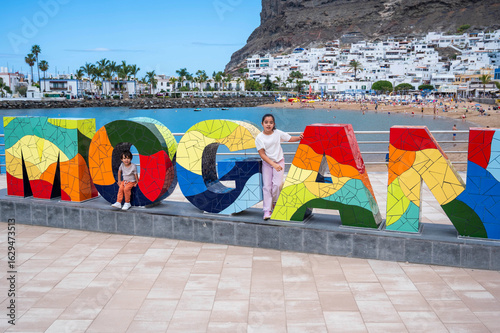 A girl and a boy are standing in front of a large sign that says 