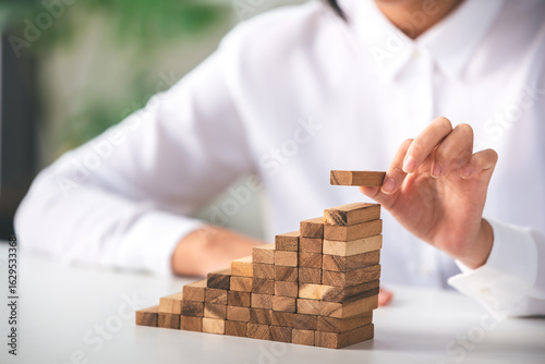 Building blocks of success, carefully stacking wooden pieces to create upward momentum and growth