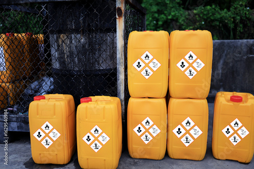 Yellow chemical tank marked with symbols indicating toxic to the environment are placed in the storage area before being properly disposed