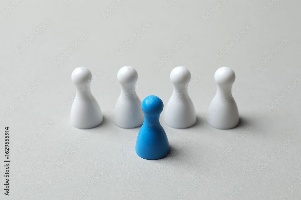 Obraz premium Blue pawn among white on gray background 