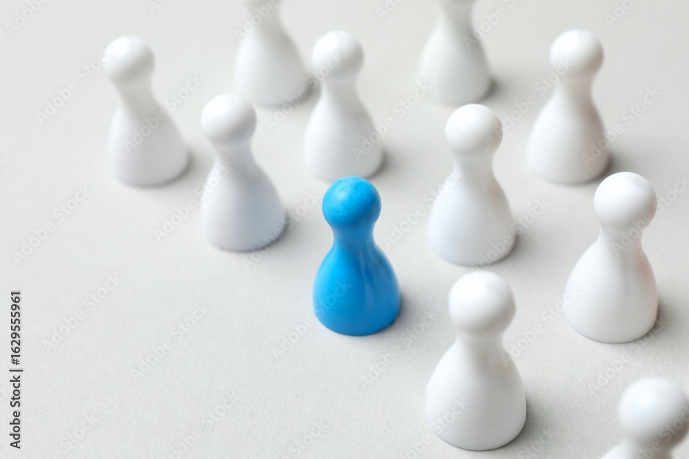 Obraz premium Blue pawn among white on the table. The concept of difference and uniqueness 