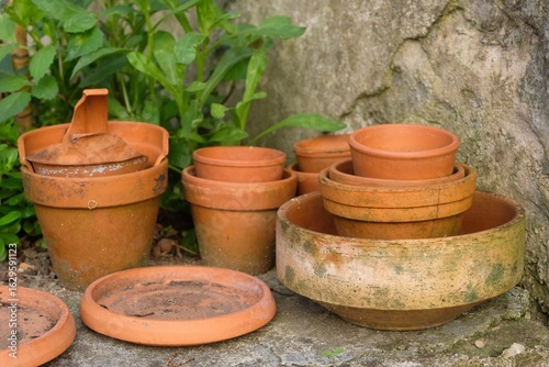 Tablou pe pânză Pots de fleurs en terre cuite vides entassés dans un coin de jardin