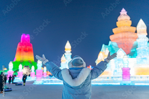Young happy female tourist enjoying at ice and snow world festival at night in Harbin, China